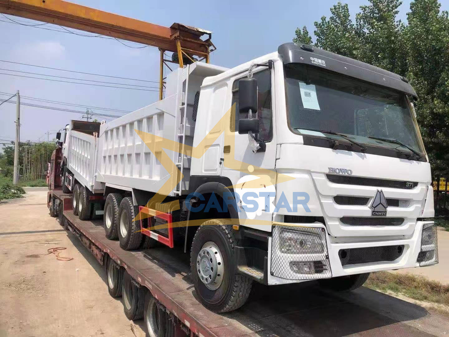 Three used dump trucks ordered by a Nigerian customer are being loaded 